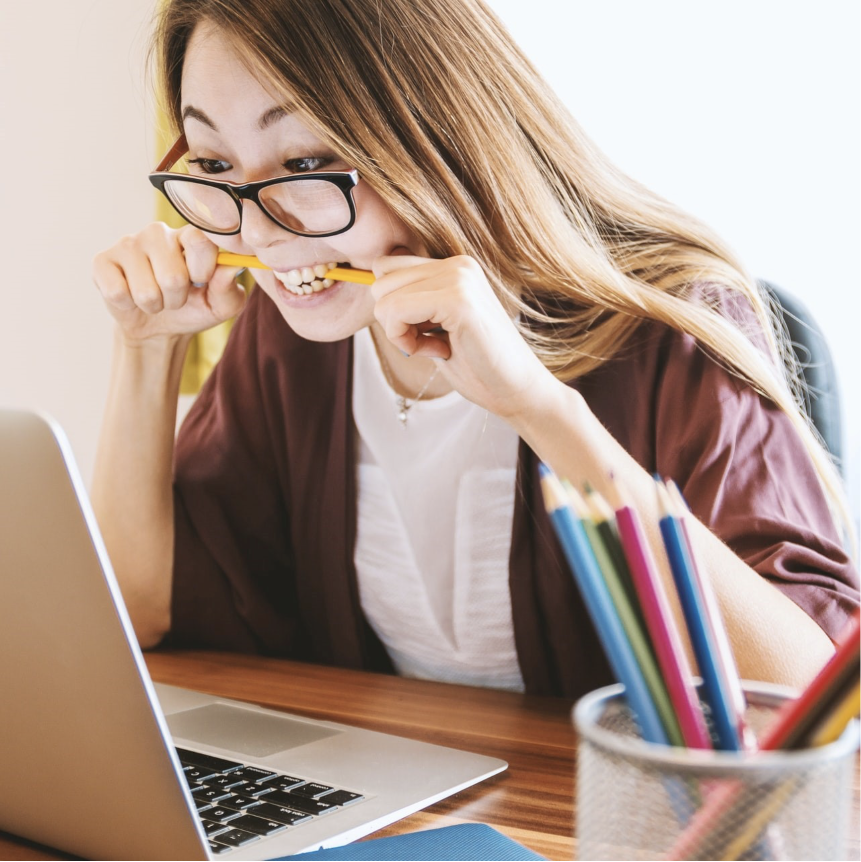 College student studying at a computer and biting her pencil
